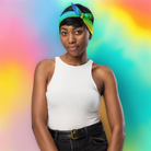 Portrait d’une femme souriante portant un bandana arc-en-ciel noué sur la tête, posant devant un fond coloré dégradé dans des tons pastel.